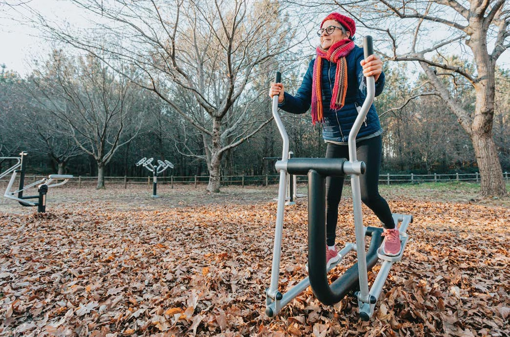 An image of a lady exercising on an outdoor gym equipment