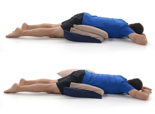 Person lying on their front with one or two pillow beneath their hips