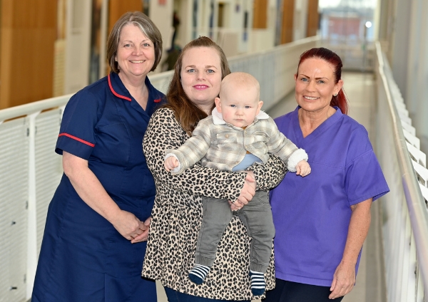 A photo of a child, his mother and two clinicians